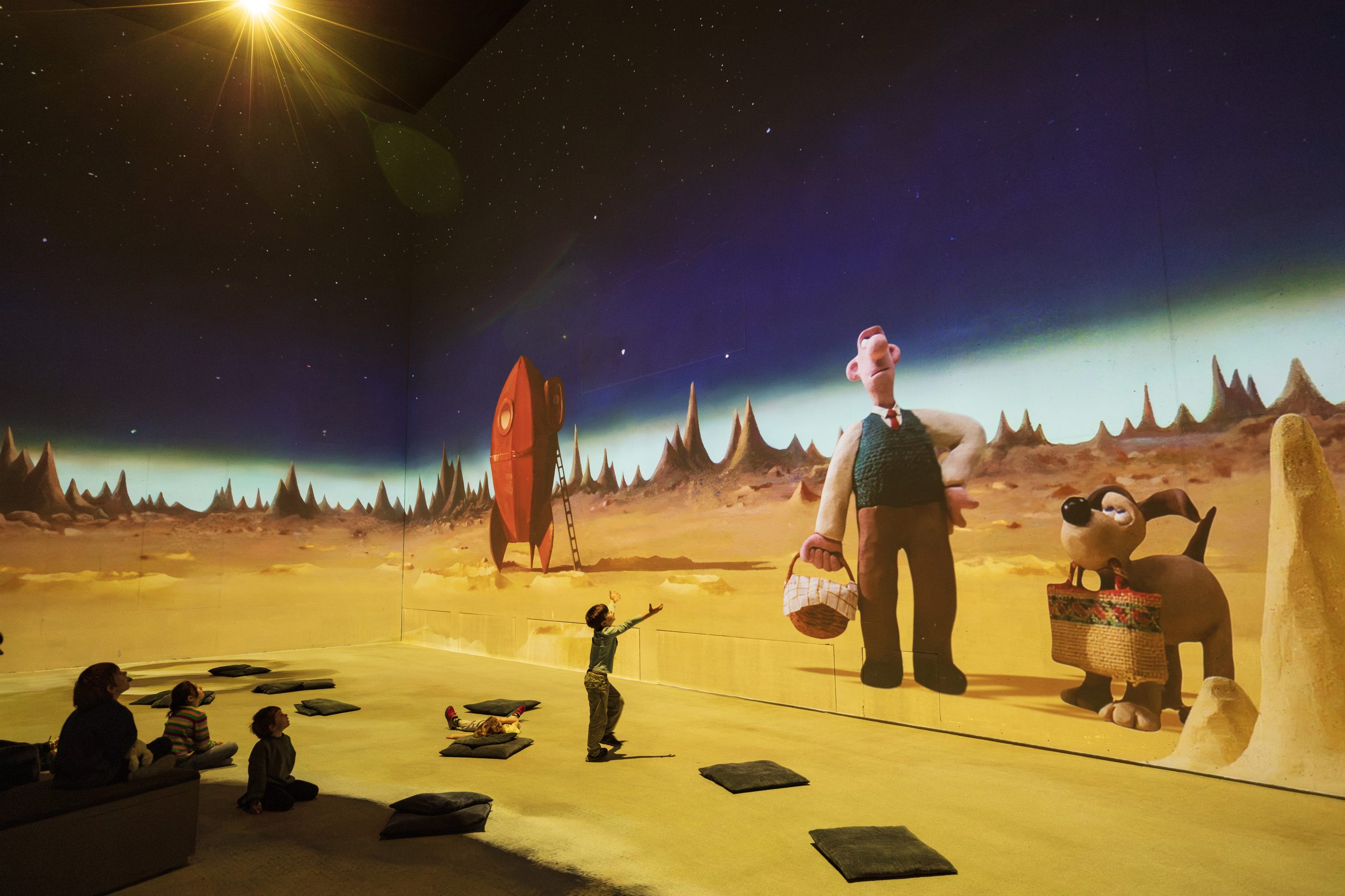 A child reaches out to Wallace & Gromit on the Moon from A Grand Day Out in the Aardman immersive experience at Lightroom