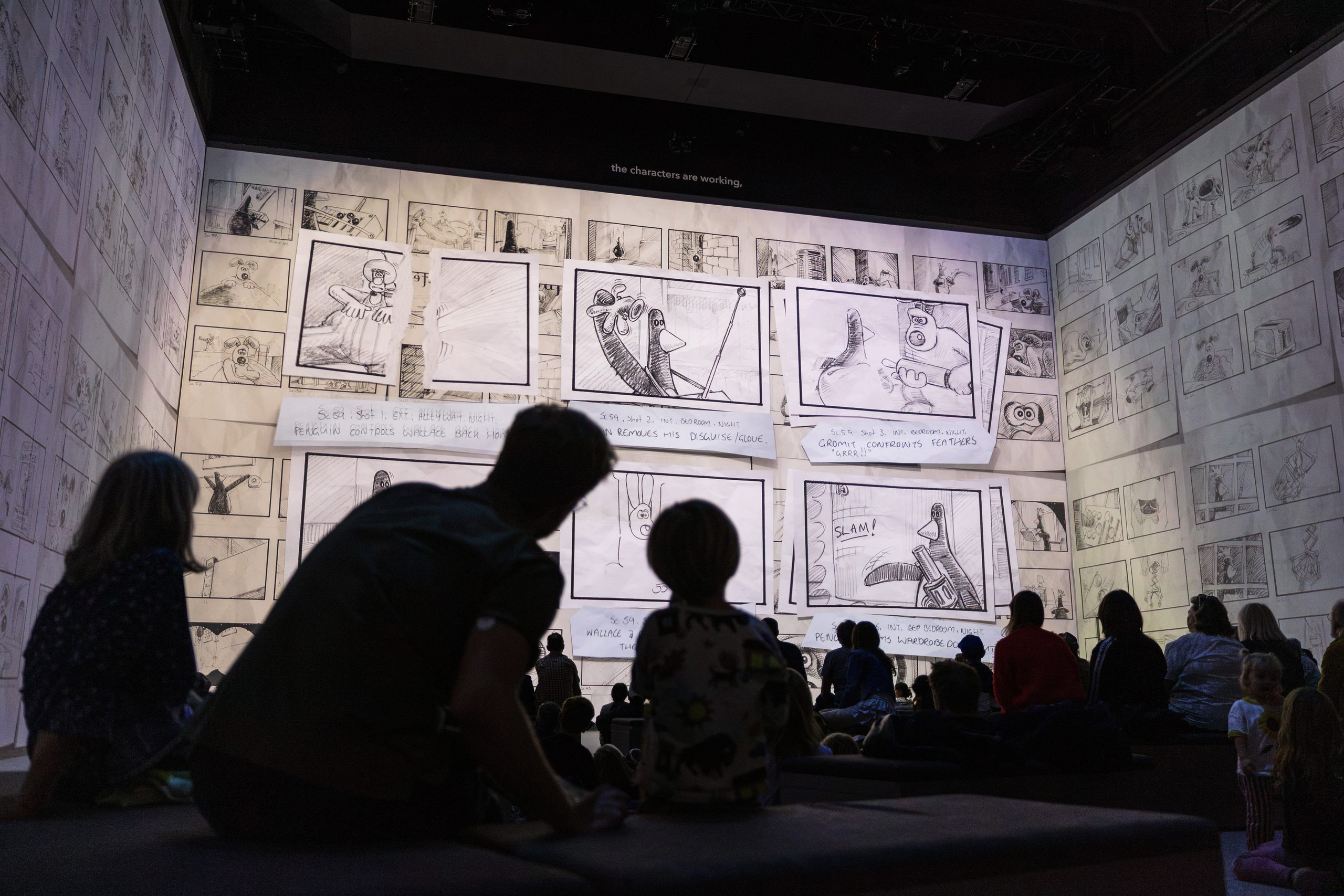 A family silhouetted against walls of hand-drawn Aardman storyboards at Lightroom