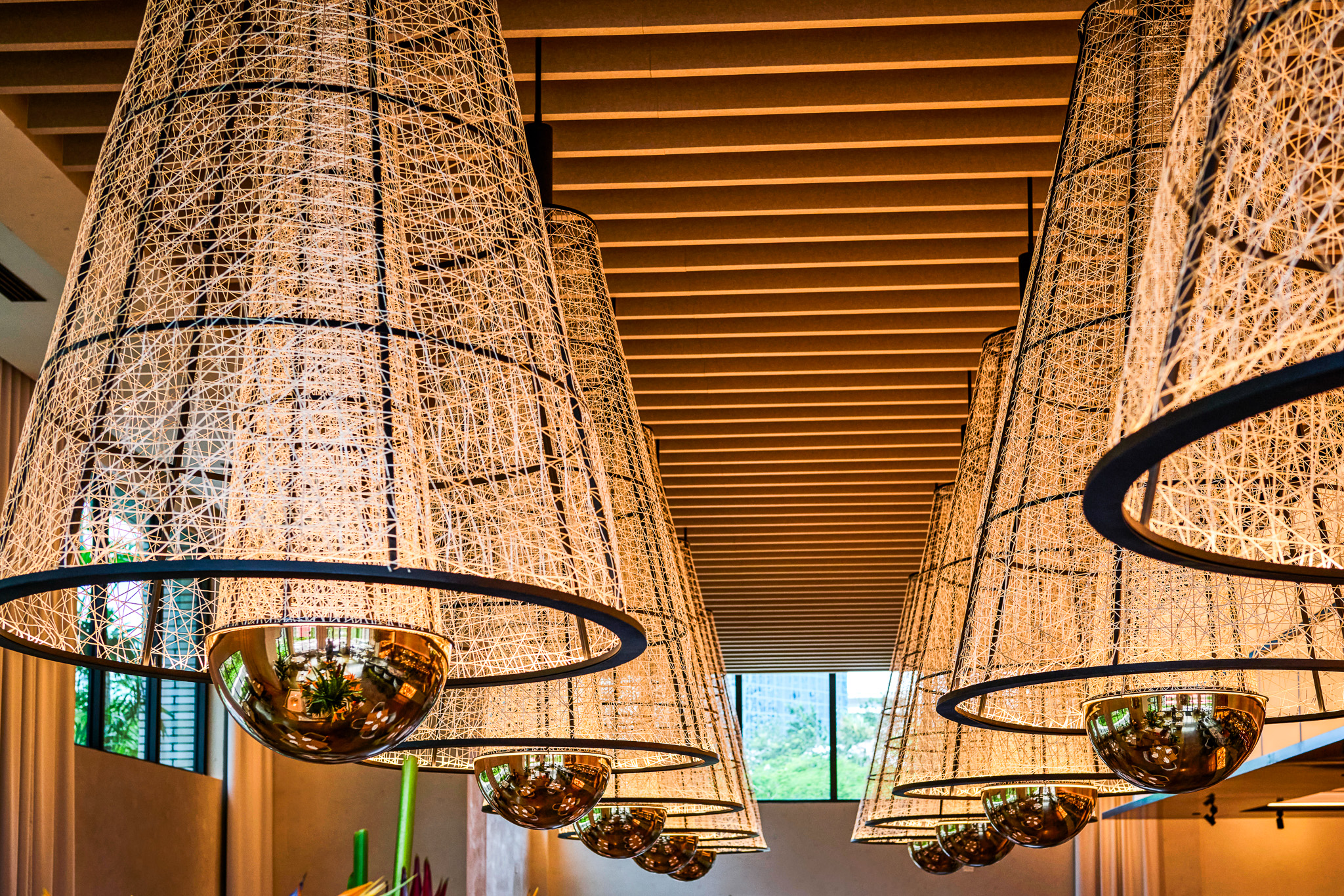 Close view of the woven conical pendants, inspired by traditional fishing traps, with mirrored domes