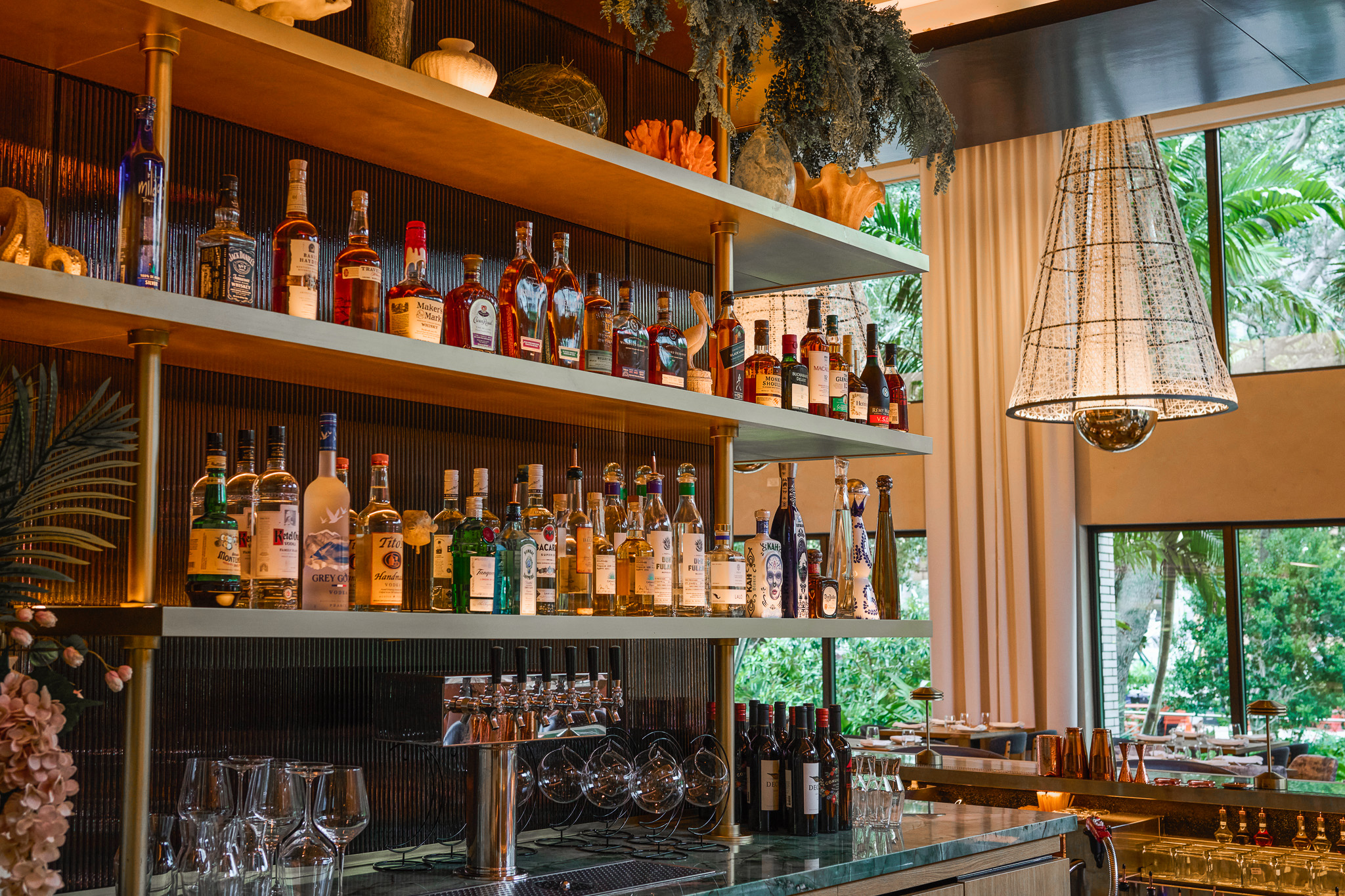 The restaurant's back bar, its shelves lined with bottles beside tall windows onto the park