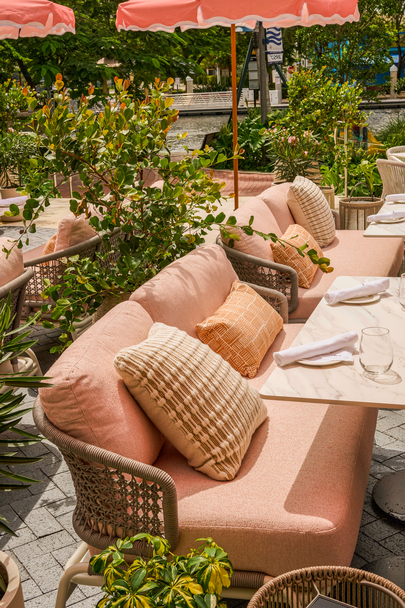 Pink cushioned banquette seating on the Sweetwaters terrace, set among tropical planting