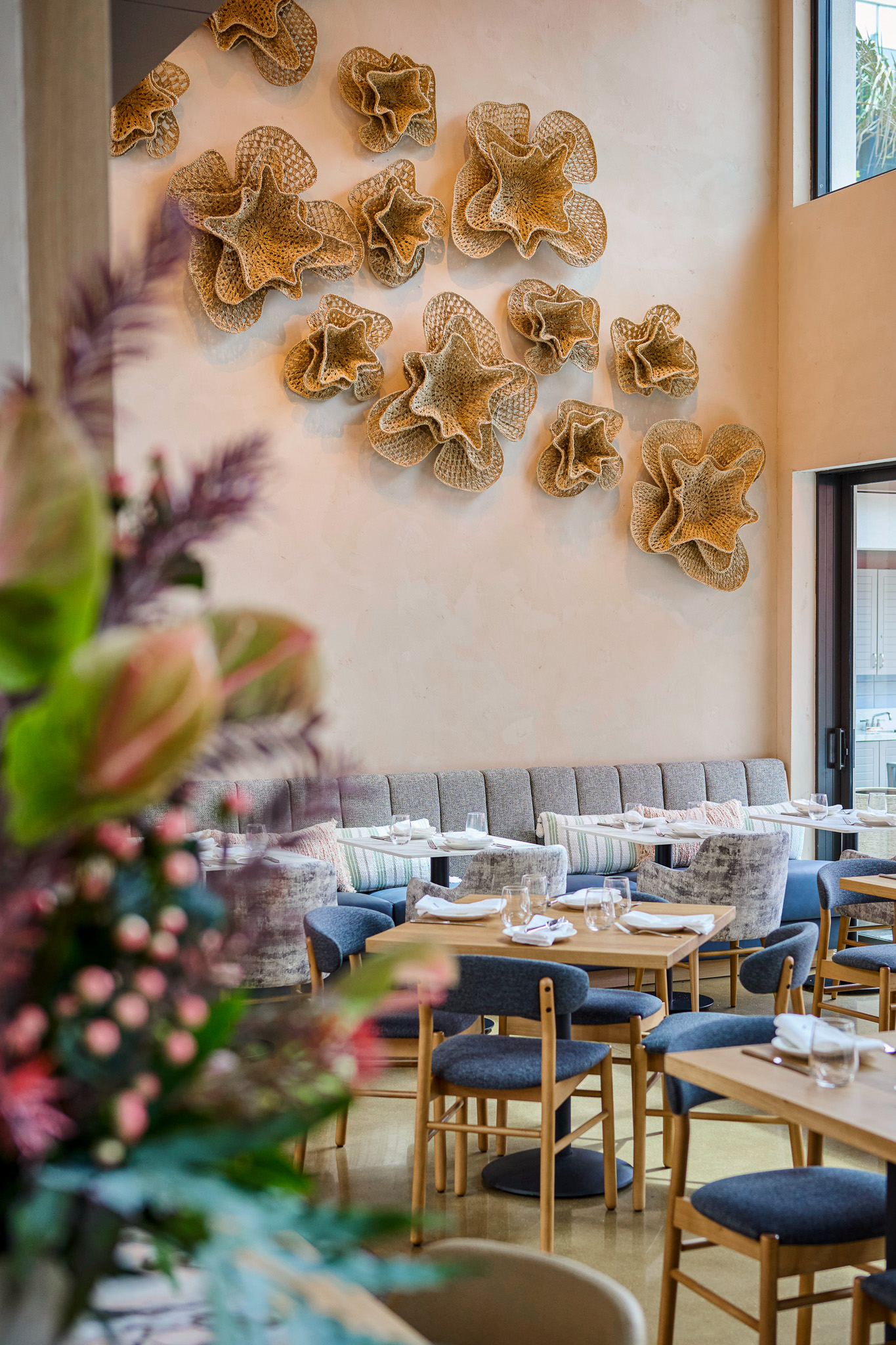 Wall installation of woven forms above banquette seating and dining tables